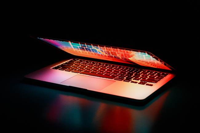 Zu sehen ist ein halbgeöffneter Laptop in dunkler Umgebung. Es geht um Daten aus dem AnyDesk-Hack im Darknet. Bild: Pexels/Junior Teixeira
