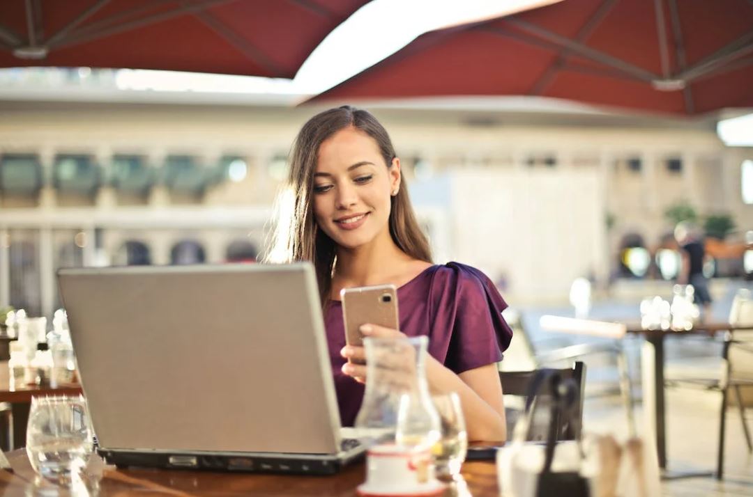 zu sehen ist eine Frau der Generation Z mit Laptop und Smartphone in einem Straßencafe. Thema ist der Cyber Resilience Act. Bild: Pexels/Andrea Piacquadio