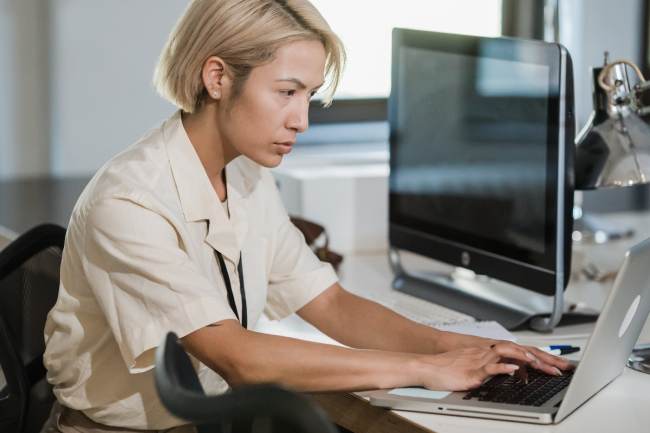 Eine Frau arbeitet konzentriert am Laptop; dank IT-Monitoring ist sie ungestört. Bild: Pexels/Mizuno K
