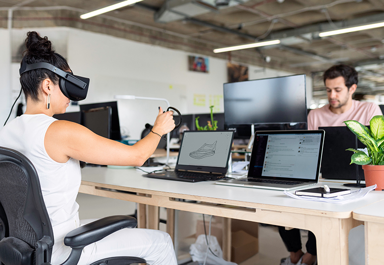 Eine Frau sitzt mit einer Virtual-Reality-Brille am Computer und arbeitet an einer Produktentwicklung. Bild: Pexels/ThisIsEngineering