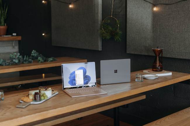 Zu sehen sind zwei Laptops auf dem Tisch in einem Café. Die nutzen Windows-11-Versionen. Bild: Unsplash/Windows
