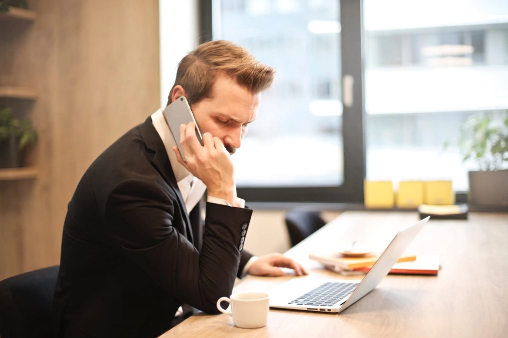 Zu sehen ist ein Mann in einem Büro, der mit dem Handy telefoniert. Thema des Artikels ist der neue Fakecall Troajaner. Bild: Pexels/Andrea Piacquadio