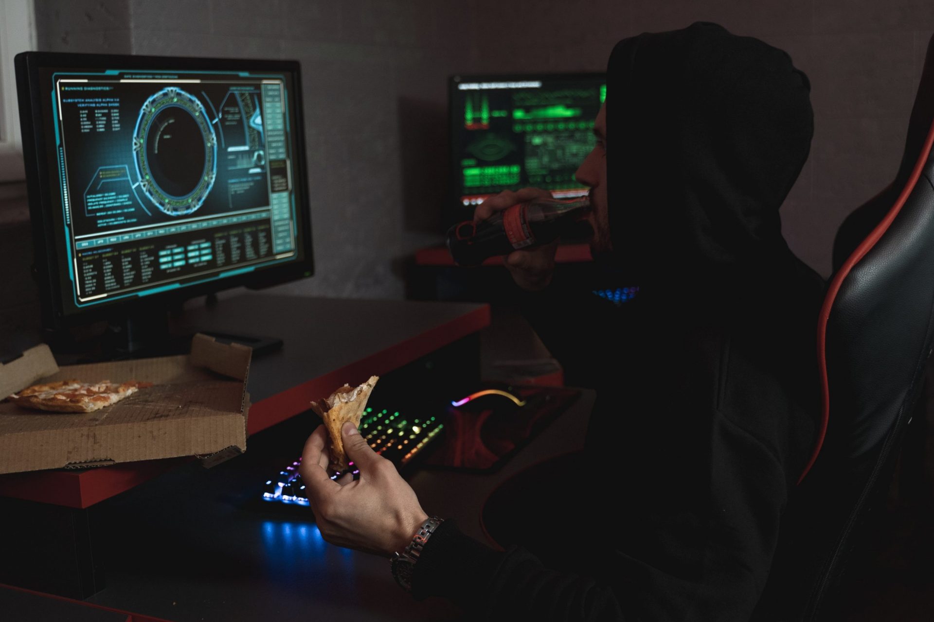 Man sieht eine Person, die im Schatten vor zwei Monitoren sitzt und einen Hacker darstellen soll. Das Thema ist die Red Team Blue Team Übung. Bild: Pexels/Tima Miroshnichenko