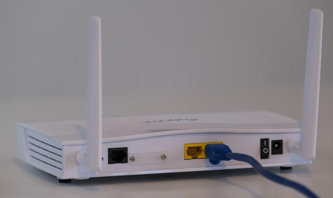 zu sehen ist ein weißer Router vor einer weißen Wand. Das Thema ist die Sicherheit von Firewalls innerhalb von Routern und die bessere Alternative, die UTM-Firewall. Bild: Unsplash/  Vergleiche Fibre